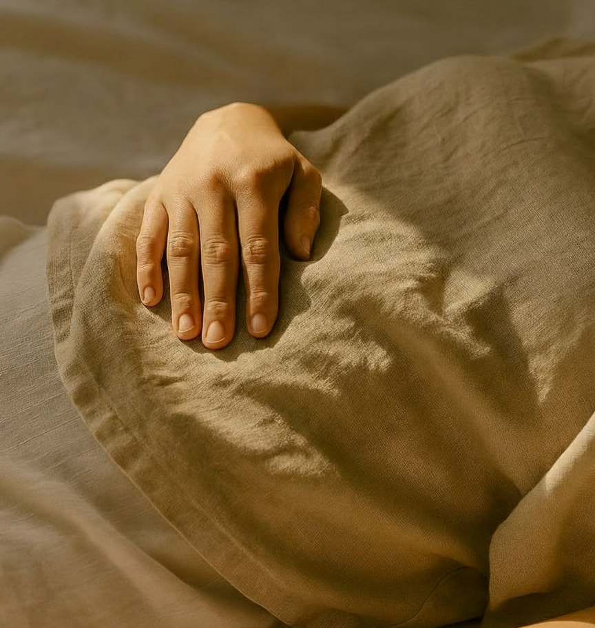 A hand resting on soft bedding — the early weeks of postpartum demand deep, sustained rest